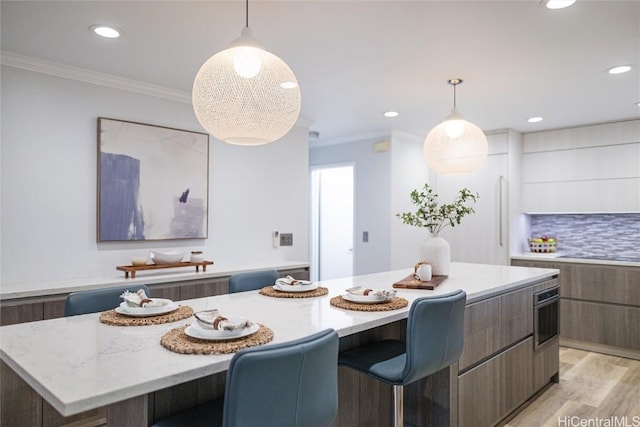 dining room featuring breakfast area, crown molding, and light wood-type flooring