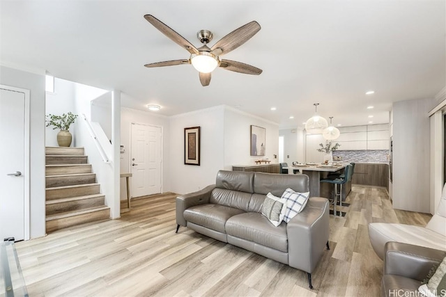 living room with crown molding, ceiling fan, and light hardwood / wood-style flooring