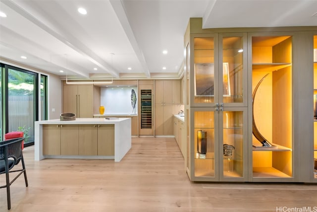 kitchen with beam ceiling, a large island, light brown cabinetry, and light hardwood / wood-style flooring