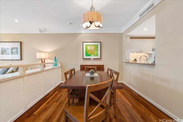 dining room featuring dark hardwood / wood-style flooring, crown molding, and an inviting chandelier