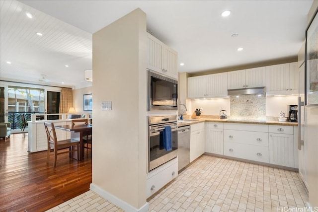 kitchen featuring backsplash, sink, light hardwood / wood-style floors, white cabinetry, and stainless steel appliances