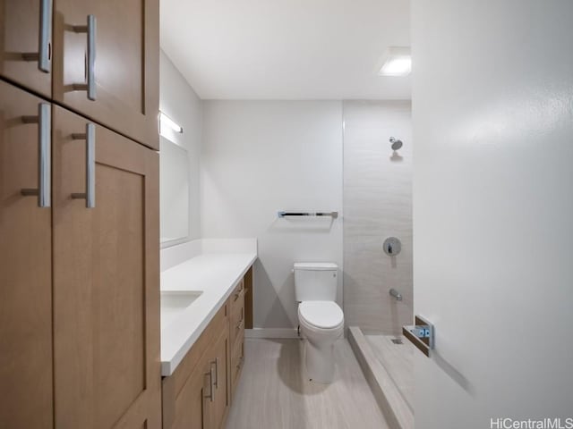 bathroom with vanity, toilet, and tiled shower