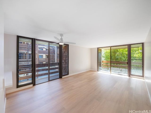 unfurnished room with ceiling fan, light hardwood / wood-style floors, and a wall of windows