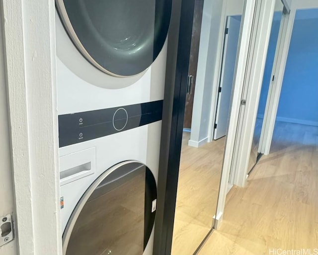 laundry area with light wood-type flooring and stacked washer and dryer