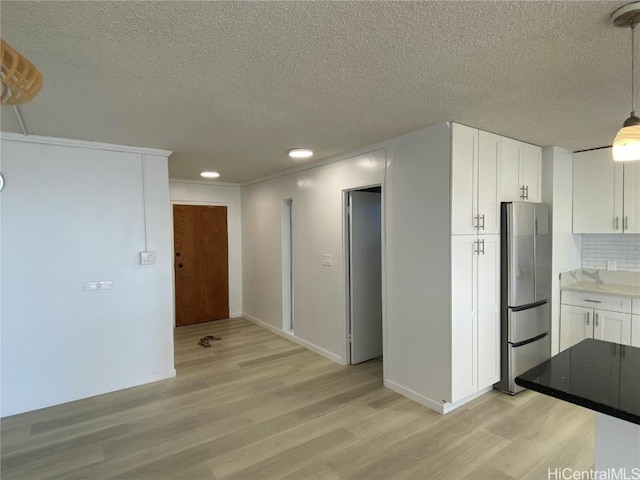 kitchen featuring decorative backsplash, decorative light fixtures, light hardwood / wood-style flooring, white cabinets, and stainless steel refrigerator