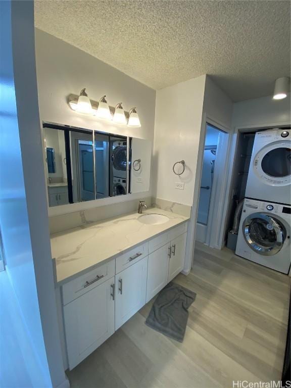 bathroom featuring a textured ceiling, vanity, stacked washer and clothes dryer, and wood-type flooring