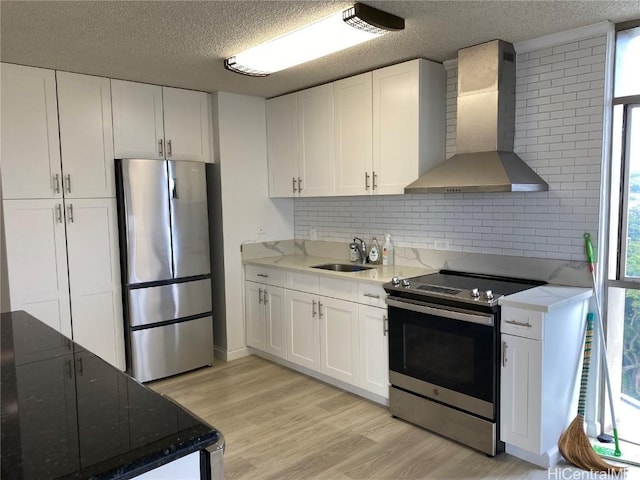 kitchen featuring white cabinets, sink, wall chimney exhaust hood, and appliances with stainless steel finishes