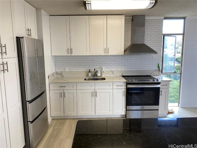 kitchen with white cabinets, sink, wall chimney exhaust hood, appliances with stainless steel finishes, and light stone counters