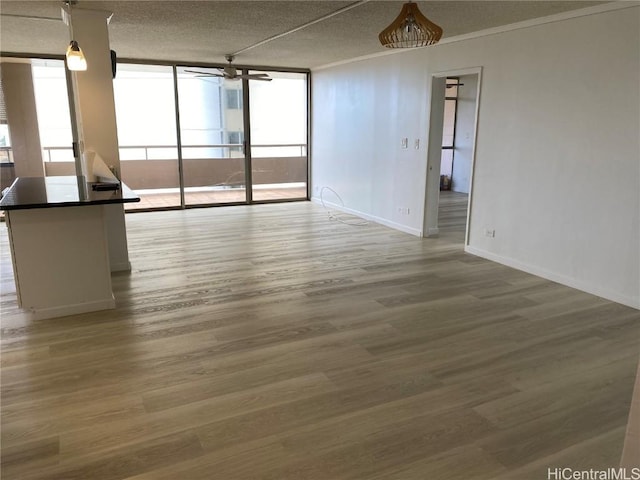 empty room featuring plenty of natural light, wood-type flooring, and a wall of windows