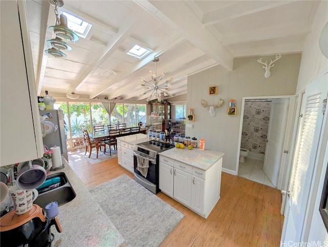 kitchen featuring lofted ceiling with skylight, light hardwood / wood-style flooring, white cabinets, and stainless steel appliances