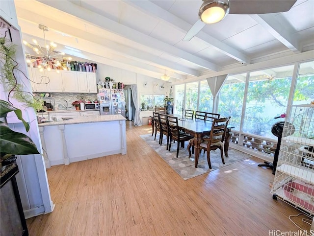 interior space featuring white cabinetry, stainless steel appliances, vaulted ceiling with beams, pendant lighting, and decorative backsplash