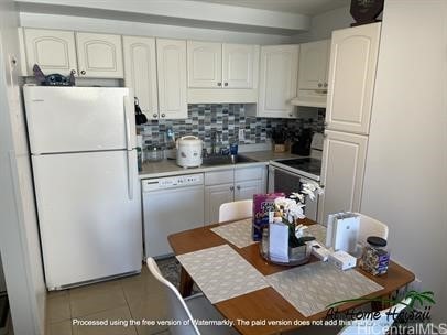 kitchen with white appliances, sink, decorative backsplash, light tile patterned floors, and white cabinetry