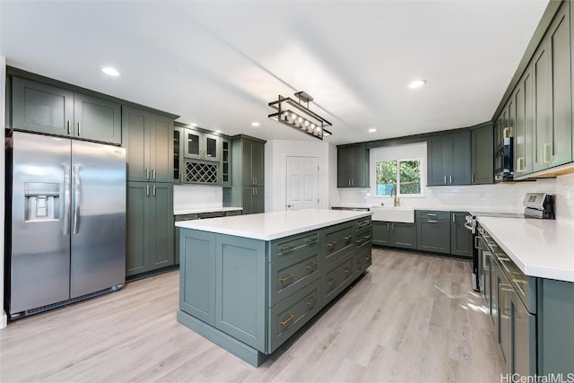 kitchen with decorative backsplash, appliances with stainless steel finishes, sink, light hardwood / wood-style flooring, and a kitchen island