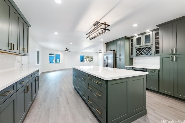 kitchen featuring ceiling fan, backsplash, stainless steel fridge, light hardwood / wood-style floors, and green cabinetry