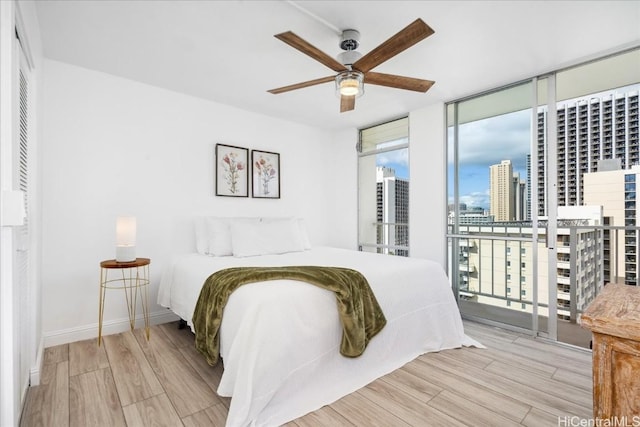 bedroom featuring ceiling fan, a wall of windows, and light hardwood / wood-style flooring