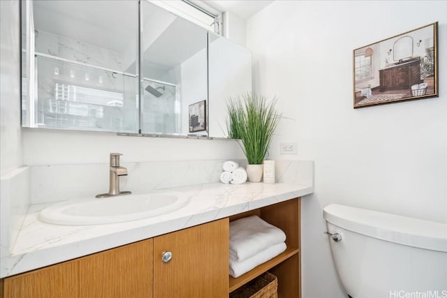 bathroom featuring vanity, a shower with shower door, and toilet