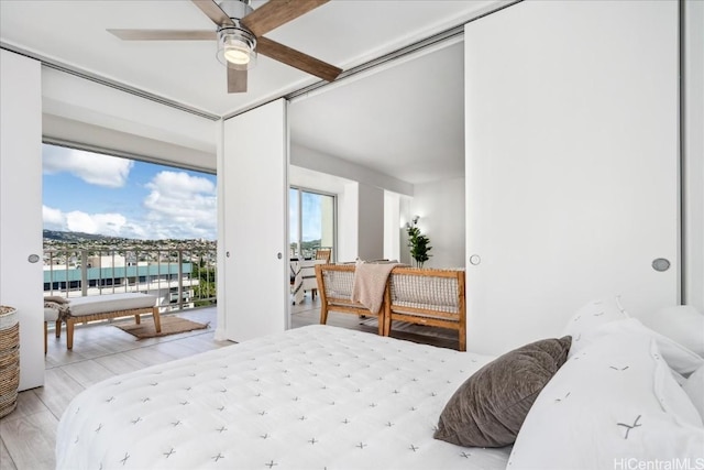 bedroom featuring ceiling fan, a water view, light wood-type flooring, and access to outside