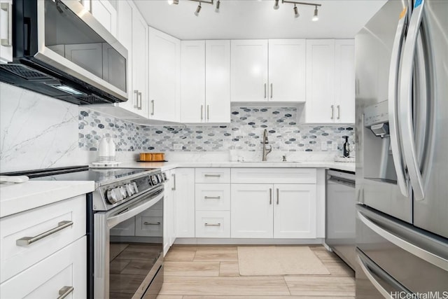 kitchen with decorative backsplash, appliances with stainless steel finishes, white cabinetry, and sink