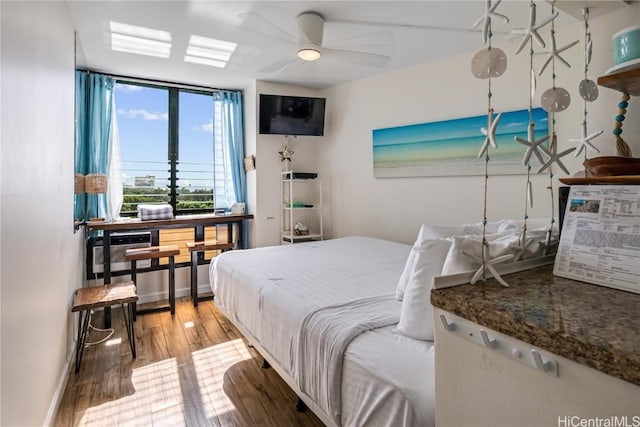 bedroom featuring floor to ceiling windows, ceiling fan, a wall mounted AC, and light wood-type flooring