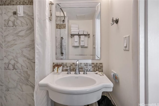 bathroom featuring tasteful backsplash, sink, and walk in shower