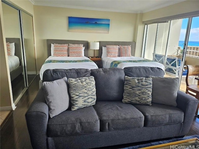 bedroom with dark hardwood / wood-style flooring, a closet, a water view, and ornamental molding