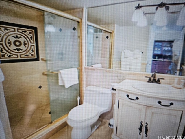 bathroom featuring a shower with door, vanity, and toilet