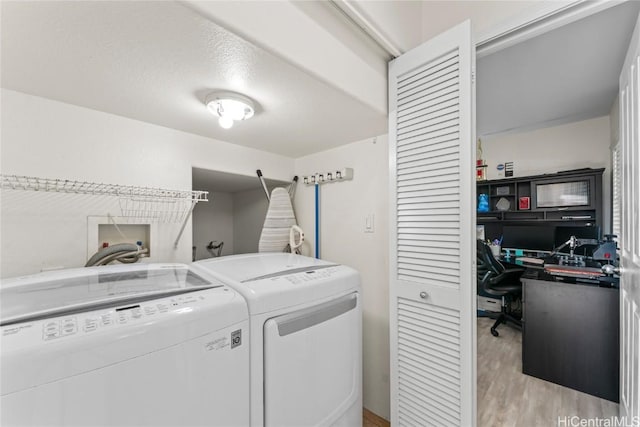 washroom featuring a textured ceiling, light wood-type flooring, and washer and clothes dryer