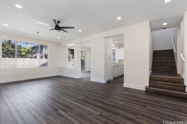 unfurnished living room with ceiling fan, sink, and dark wood-type flooring