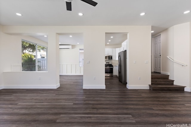 unfurnished living room with a wall mounted AC, dark hardwood / wood-style floors, and ceiling fan