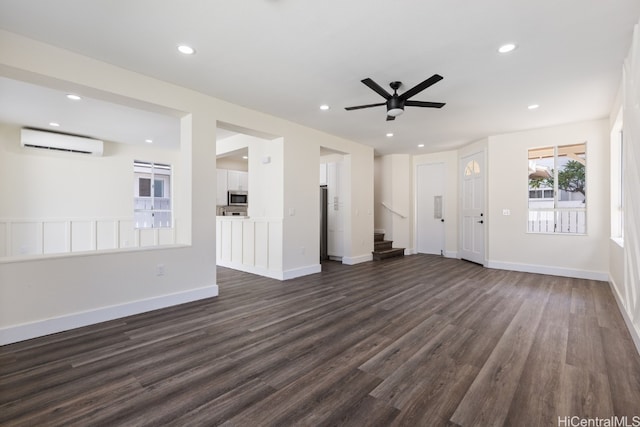 unfurnished living room featuring ceiling fan, dark wood-type flooring, and a wall mounted air conditioner