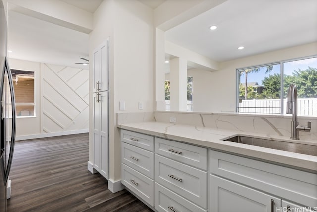 kitchen featuring dark wood-type flooring, white cabinetry, sink, and light stone countertops