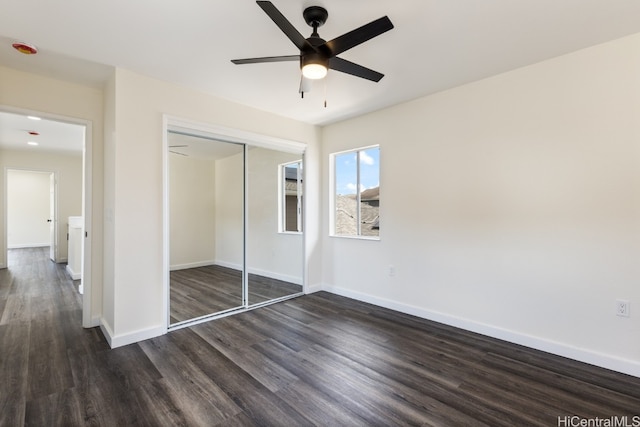 unfurnished bedroom featuring a closet, dark wood-type flooring, and ceiling fan