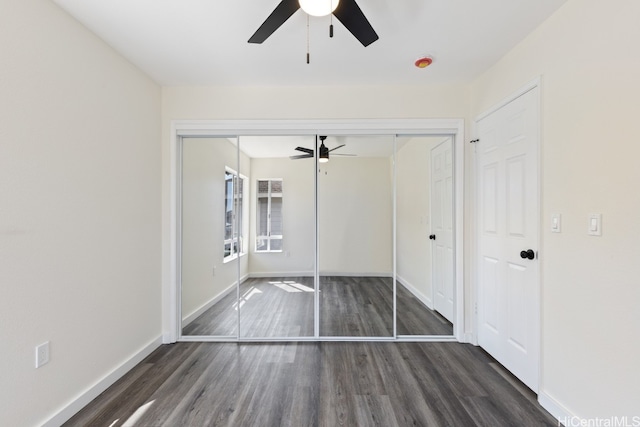 unfurnished bedroom featuring ceiling fan, dark hardwood / wood-style flooring, and a closet