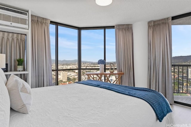 bedroom featuring access to exterior, hardwood / wood-style floors, an AC wall unit, and floor to ceiling windows