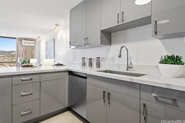 kitchen featuring gray cabinetry, sink, stainless steel dishwasher, light stone countertops, and a textured ceiling