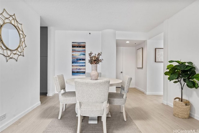 dining area with light hardwood / wood-style floors and a textured ceiling