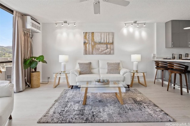 living room featuring floor to ceiling windows, ceiling fan, a textured ceiling, and light wood-type flooring