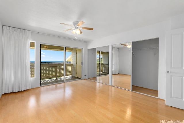 unfurnished bedroom with access to outside, ceiling fan, two closets, and light wood-type flooring