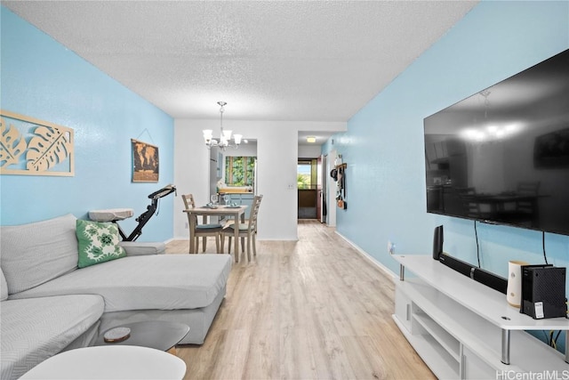 living room featuring light hardwood / wood-style floors, a textured ceiling, and a chandelier