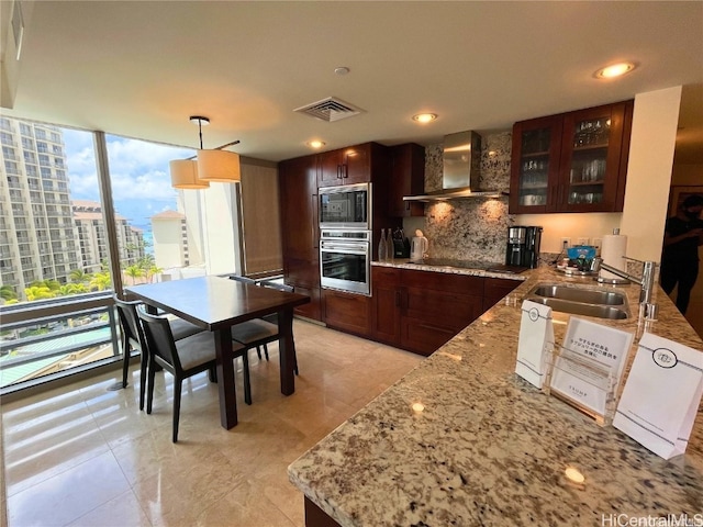 kitchen with backsplash, wall chimney exhaust hood, sink, black appliances, and pendant lighting