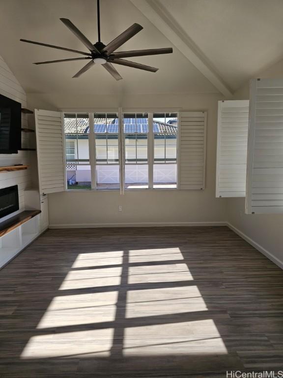 unfurnished living room with vaulted ceiling with beams, ceiling fan, a large fireplace, and dark hardwood / wood-style floors