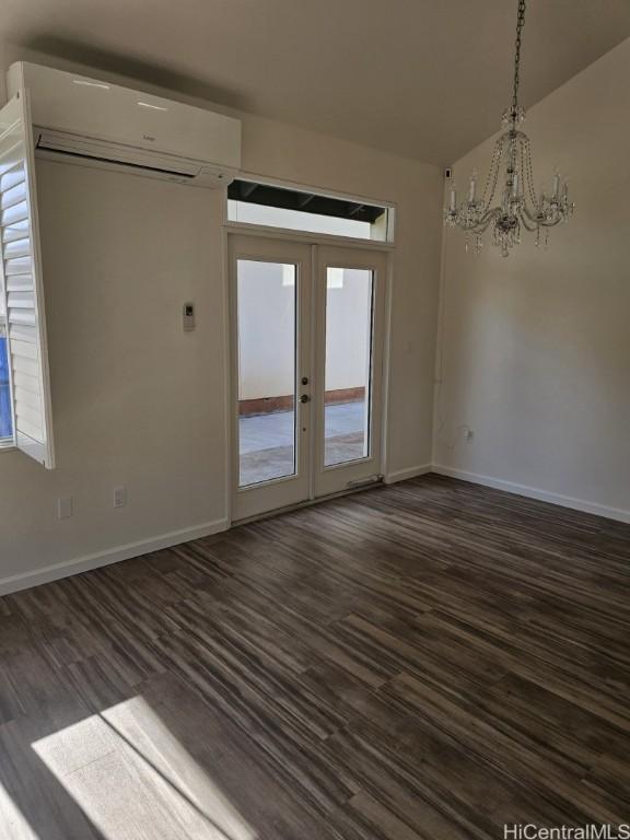 spare room with french doors, dark hardwood / wood-style floors, and a wall unit AC