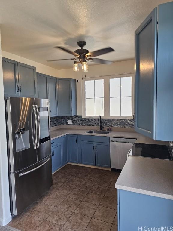 kitchen featuring backsplash, stainless steel appliances, ceiling fan, sink, and blue cabinetry