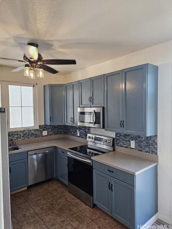 kitchen with sink, ceiling fan, blue cabinetry, tasteful backsplash, and stainless steel appliances