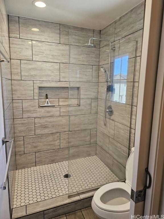 bathroom with a tile shower and toilet