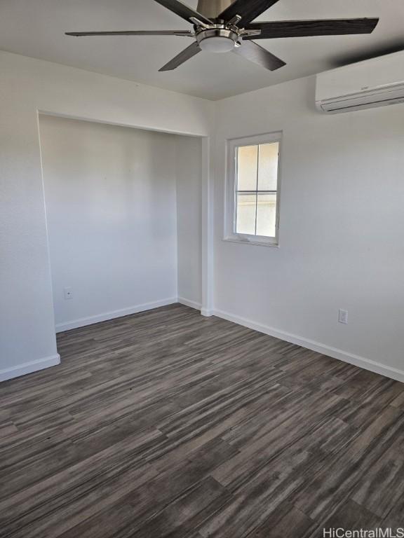 spare room with an AC wall unit, ceiling fan, and dark hardwood / wood-style flooring