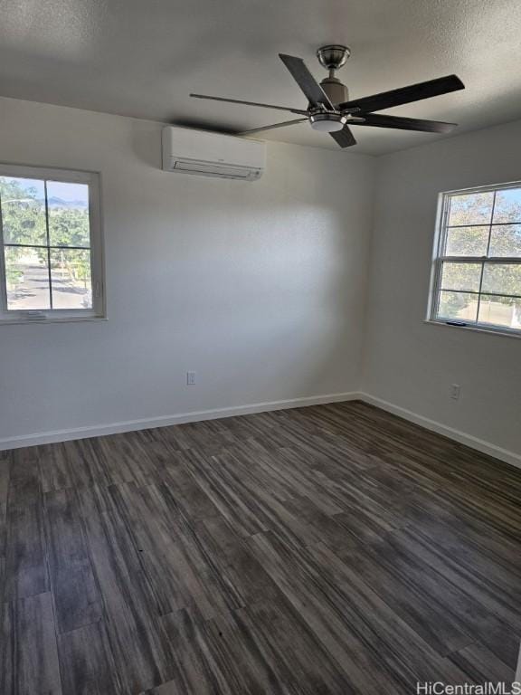 empty room with a textured ceiling, dark hardwood / wood-style flooring, and a wall unit AC