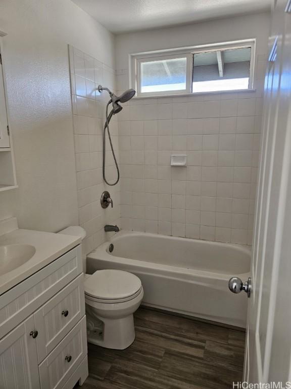 full bathroom with vanity, hardwood / wood-style floors, tiled shower / bath combo, and toilet