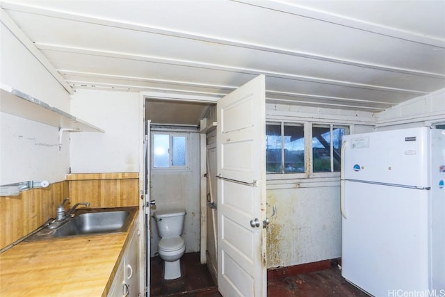 kitchen with sink, white fridge, and wood counters