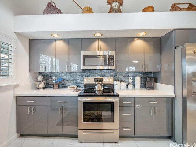 kitchen featuring tasteful backsplash, gray cabinetry, and appliances with stainless steel finishes